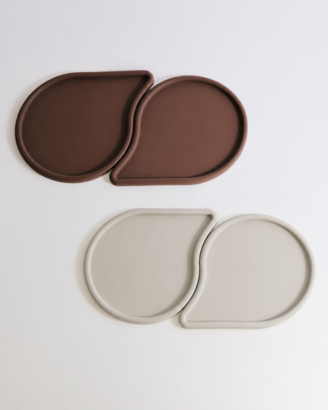 Two sets of brown and beige oval coasters on a light gray background
