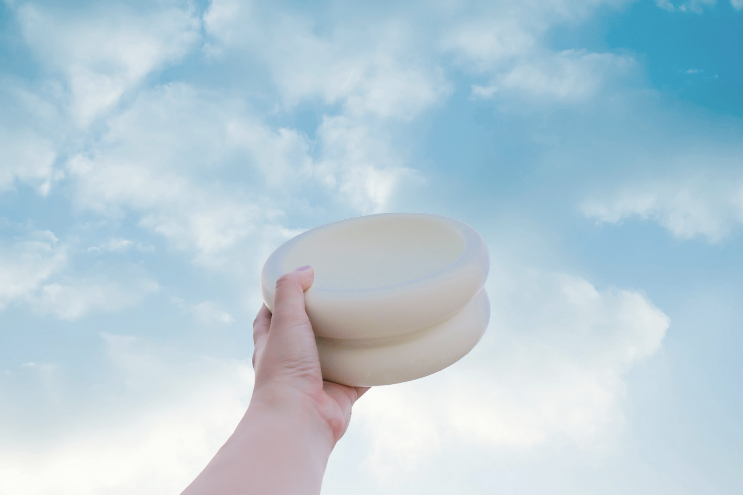 modern elevated cat bowl that prevents whisker fatigue in white ceramic raised to a blue sky with clouds