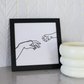 single line art of hand and paw reaching in black frame by catenary home modern cat furniture company  on marble counter with white backsplash and elevated cat bowls next to it